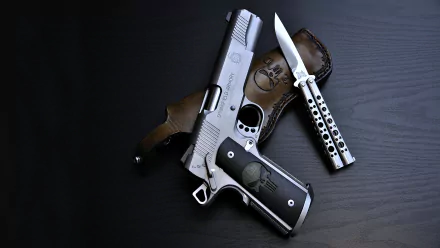 A Springfield Armory pistol and a knife are displayed on a dark wooden surface, creating a striking HD desktop wallpaper with a focus on man-made weapons.