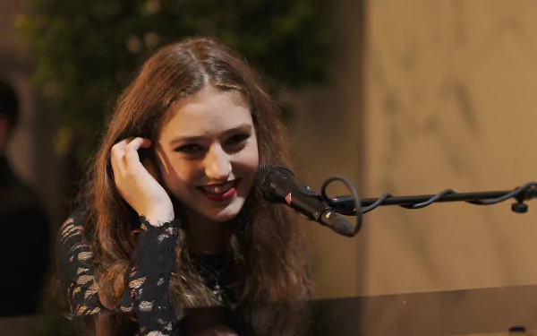 HD desktop wallpaper featuring Birdy, the English singer, smiling while performing at a piano, exuding passion for music in an intimate setting.