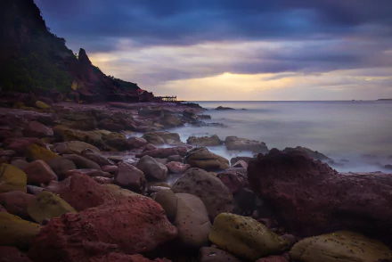 Merimbula on NSW's Sapphire Coast: rocky seashore with misty waves and a dramatic twilight sky — 5K Ultra HD PC desktop wallpaper/background.
