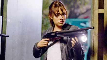 Emma Stone in a gritty scene from the movie Zombieland, holding a shotgun and exuding confidence, serves as an engaging HD desktop wallpaper and background.