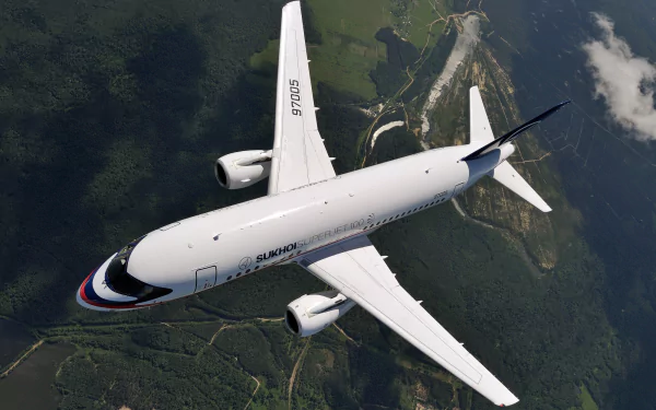HD PC desktop wallpaper of a Sukhoi SuperJet 100 jet airplane vehicle in flight, top-down view over green terrain and a winding river beneath a dramatic sky.