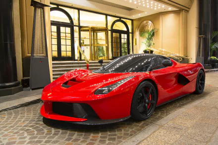 Red Ferrari LaFerrari supercar parked in front of a luxurious mansion entrance at night, featured in a high-definition desktop wallpaper and background.