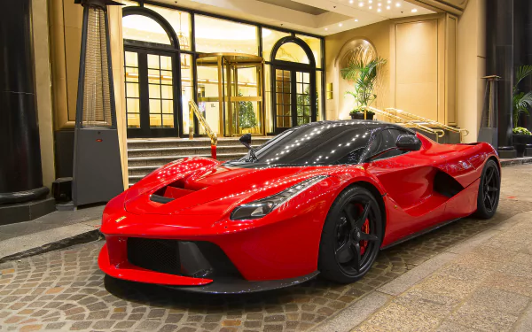 Red Ferrari LaFerrari supercar parked in front of a luxurious mansion entrance at night, featured in a high-definition desktop wallpaper and background.