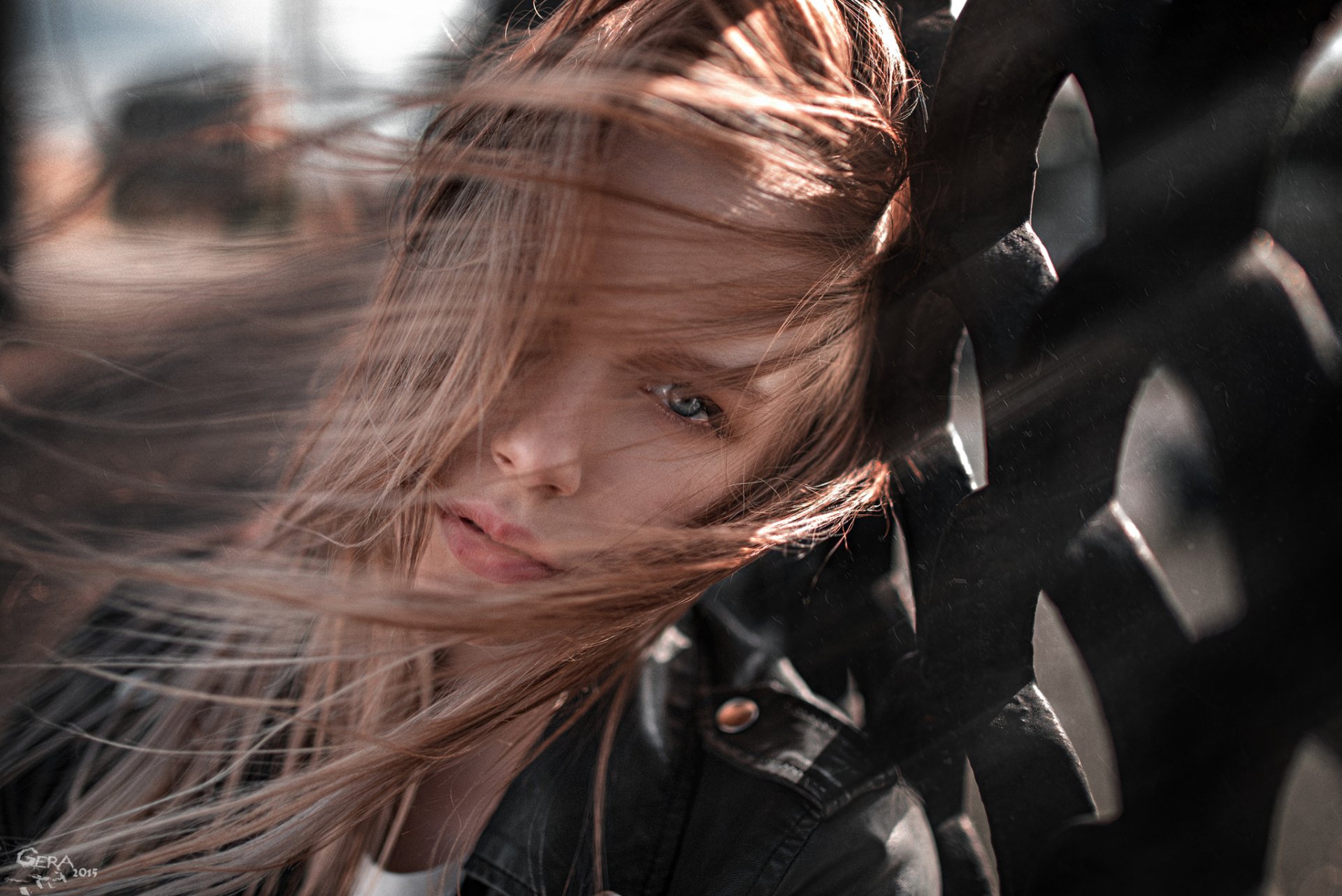 A close-up of a blonde model with blue eyes, her hair flowing dramatically in the wind against a textured background, creating an engaging and dynamic desktop wallpaper.