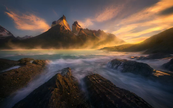 Stunning HD wallpaper of Torres del Paine in Patagonia, Chile, featuring rugged mountains, flowing water, and a vibrant sunset sky over pristine natural landscape.