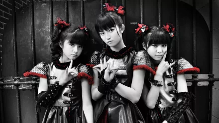 A striking black-and-white image of three Japanese metal idols from Babymetal, showcasing their unique heavy metal style with bold costumes and dramatic poses.