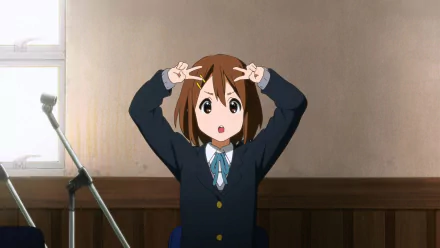 HD anime desktop wallpaper featuring Yui Hirasawa from K-ON! striking a playful pose in a classroom setting.