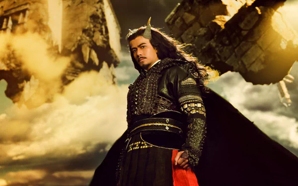 HD PC desktop wallpaper: dramatic movie still from The Monkey King showing a robed, armored Monkey King figure standing before a stormy, golden sky and crumbling stone pillars.