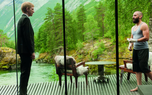Ex Machina: two men stand separated by floor-to-ceiling glass in a modern cabin overlooking a green fjord, a sheep on the deck. 4K Ultra HD PC Desktop Wallpaper and Background