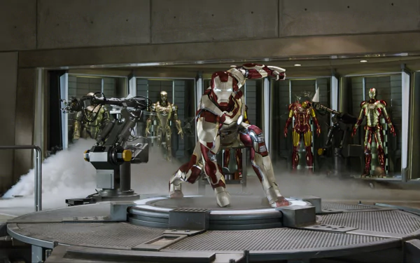 HD PC desktop wallpaper from the Iron Man 3 movie: Iron Man in red-and-gold armor kneels on a lit platform in his workshop, with multiple suits displayed behind.