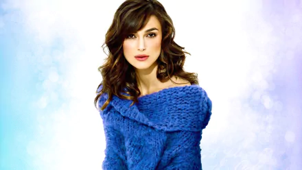 Keira Knightley poses elegantly in a blue sweater, featuring soft waves in her hair against a light backdrop. This image serves as an HD wallpaper for desktop backgrounds.