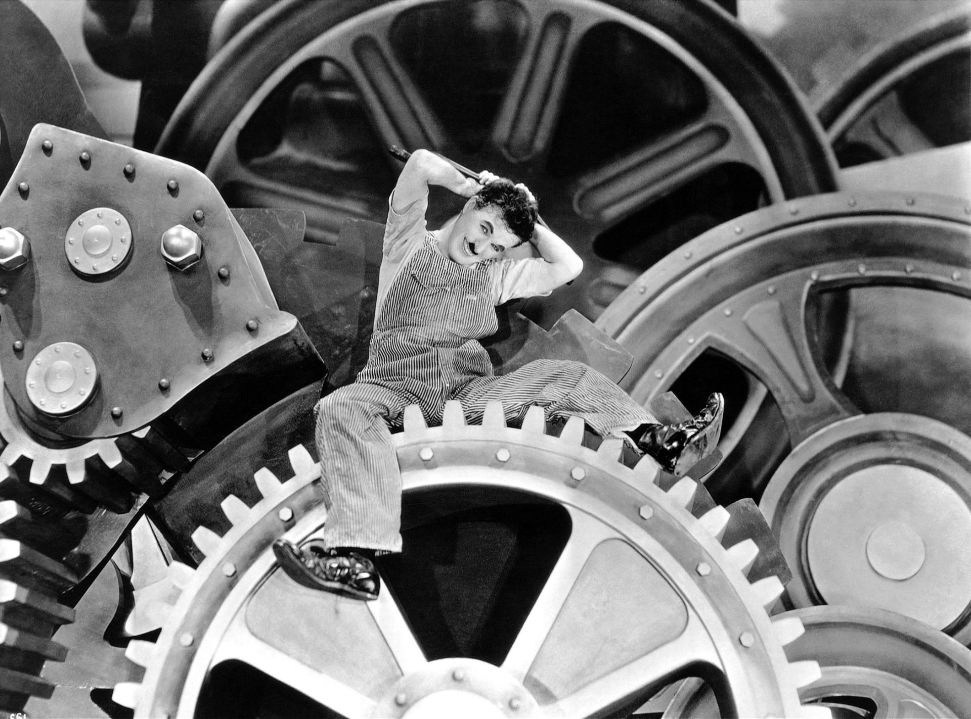 Black and white HD desktop wallpaper of Charlie Chaplin in the iconic factory scene from the movie Modern Times.
