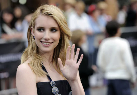 Emma Roberts waves and smiles at an event, showcasing her stylish look. This vibrant image serves as a 4K Ultra HD desktop wallpaper and background for fans.