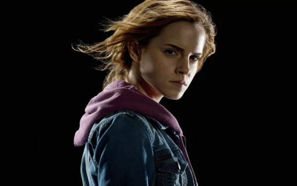 HD desktop wallpaper featuring Hermione Granger, portrayed by Emma Watson, with a striking pose and wind-swept hair against a dark background.