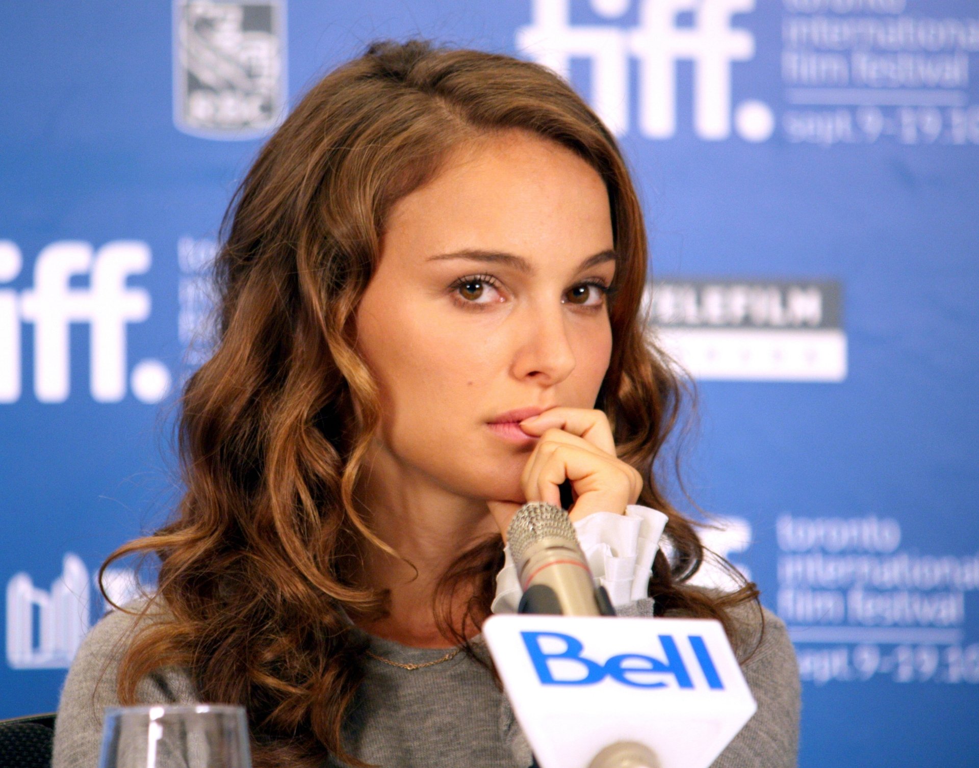 Close-up of celebrity Natalie Portman speaking at a press event, featured in a 4K Ultra HD PC desktop wallpaper with a blue backdrop displaying event logos.