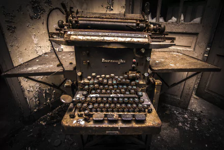 4K Ultra HD desktop wallpaper of an old, weathered Burroughs typewriter in a dim, abandoned setting showcasing man-made vintage technology.