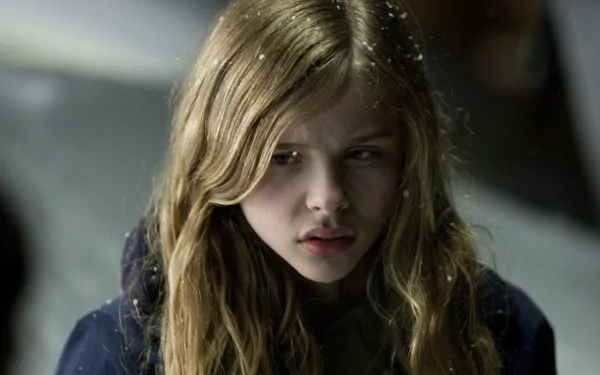 Chloë Grace Moretz stars in Let Me In, captured in this HD desktop wallpaper. The image evokes a haunting atmosphere, showcasing her intense expression against a snowy backdrop.