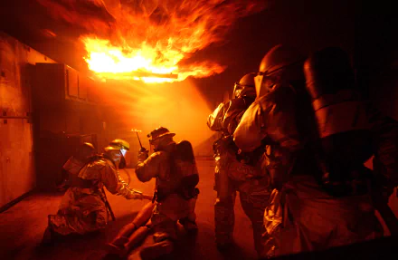 A dramatic image of firefighters in action, battling flames in a smoky environment. This HD wallpaper captures the intensity and bravery of fire rescue operations.