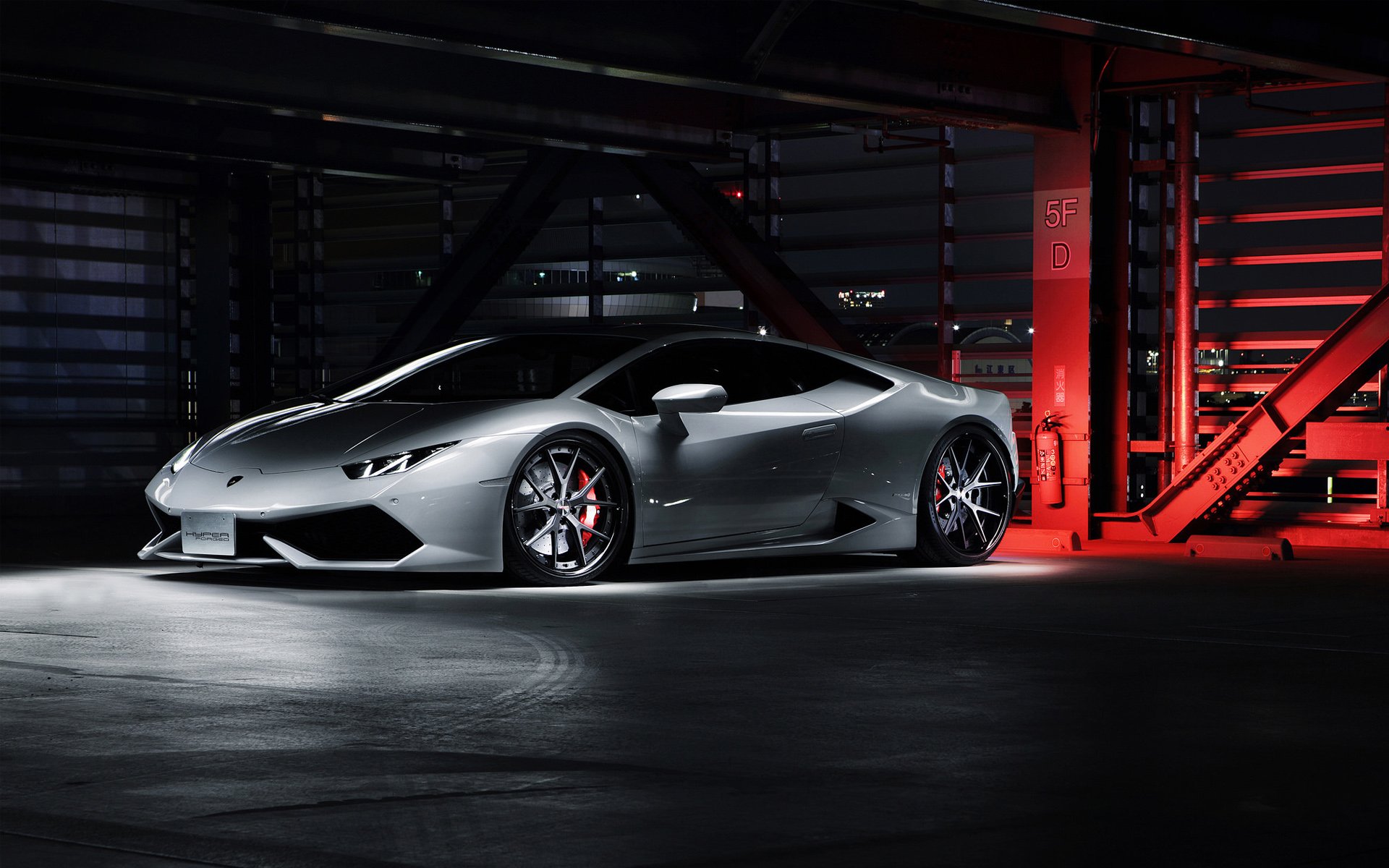 HD PC desktop wallpaper/background: silver Lamborghini Huracan sports vehicle parked in a dim industrial garage, lit by dramatic red accent lighting.