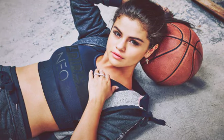 Selena Gomez poses confidently with a basketball, wearing Adidas activewear. This HD desktop wallpaper captures her dynamic style and passion for music and sports.