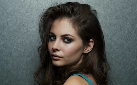 A captivating HD wallpaper featuring celebrity Willa Holland, showcasing her striking profile against a textured gray background.