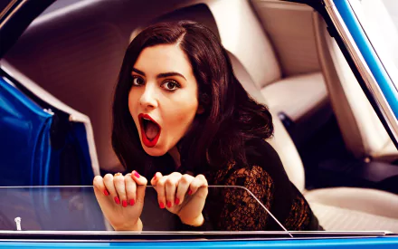 HD PC desktop wallpaper featuring Charli XCX with an expressive pose inside a blue car, capturing a vibrant and dynamic music-themed aesthetic.