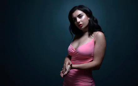 HD PC desktop wallpaper featuring Charli XCX in a pink dress against a dark background, representing music and style.