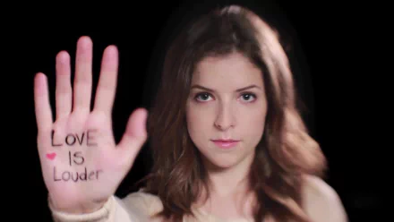 A striking HD desktop wallpaper featuring Anna Kendrick holding up her hand with LOVE IS LOUDER written on it, emphasizing a powerful message of love and support.
