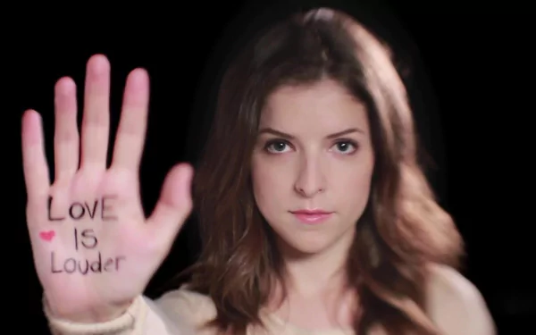 A striking HD desktop wallpaper featuring Anna Kendrick holding up her hand with LOVE IS LOUDER written on it, emphasizing a powerful message of love and support.