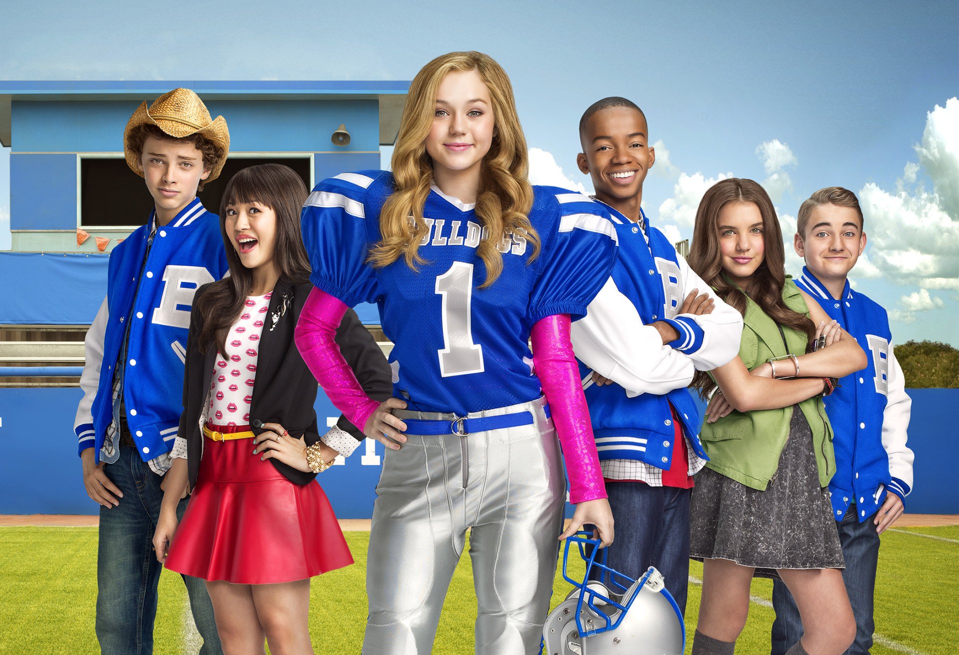 HD desktop wallpaper featuring the main cast of the TV show Bella and the Bulldogs, standing confidently on a football field with a blue sky backdrop.