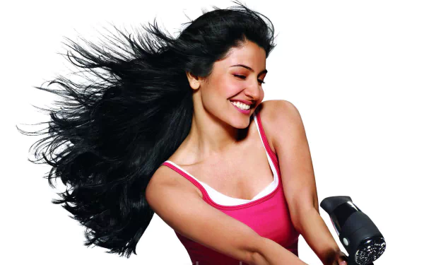 HD desktop wallpaper featuring celebrity Anushka Sharma with flowing hair, smiling brightly against a white background.