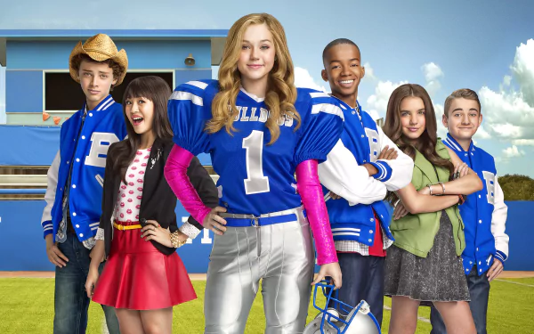 HD desktop wallpaper featuring the main cast of the TV show Bella and the Bulldogs, standing confidently on a football field with a blue sky backdrop.