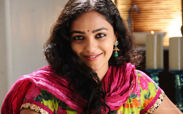 HD desktop wallpaper featuring celebrity Nithya Menon smiling warmly, dressed in a colorful traditional outfit with a pink dupatta.