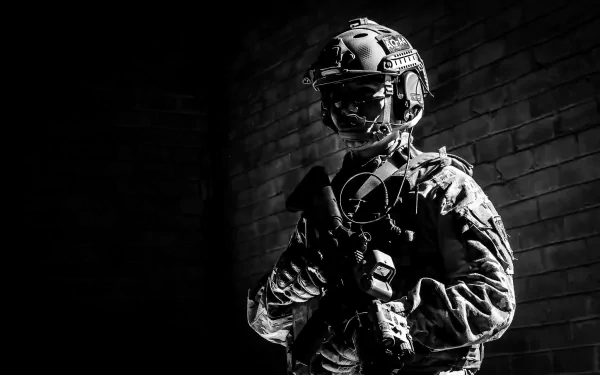 A monochrome image of a soldier in tactical gear, standing with a weapon, set against a dark brick background, making for a striking military-themed HD desktop wallpaper.