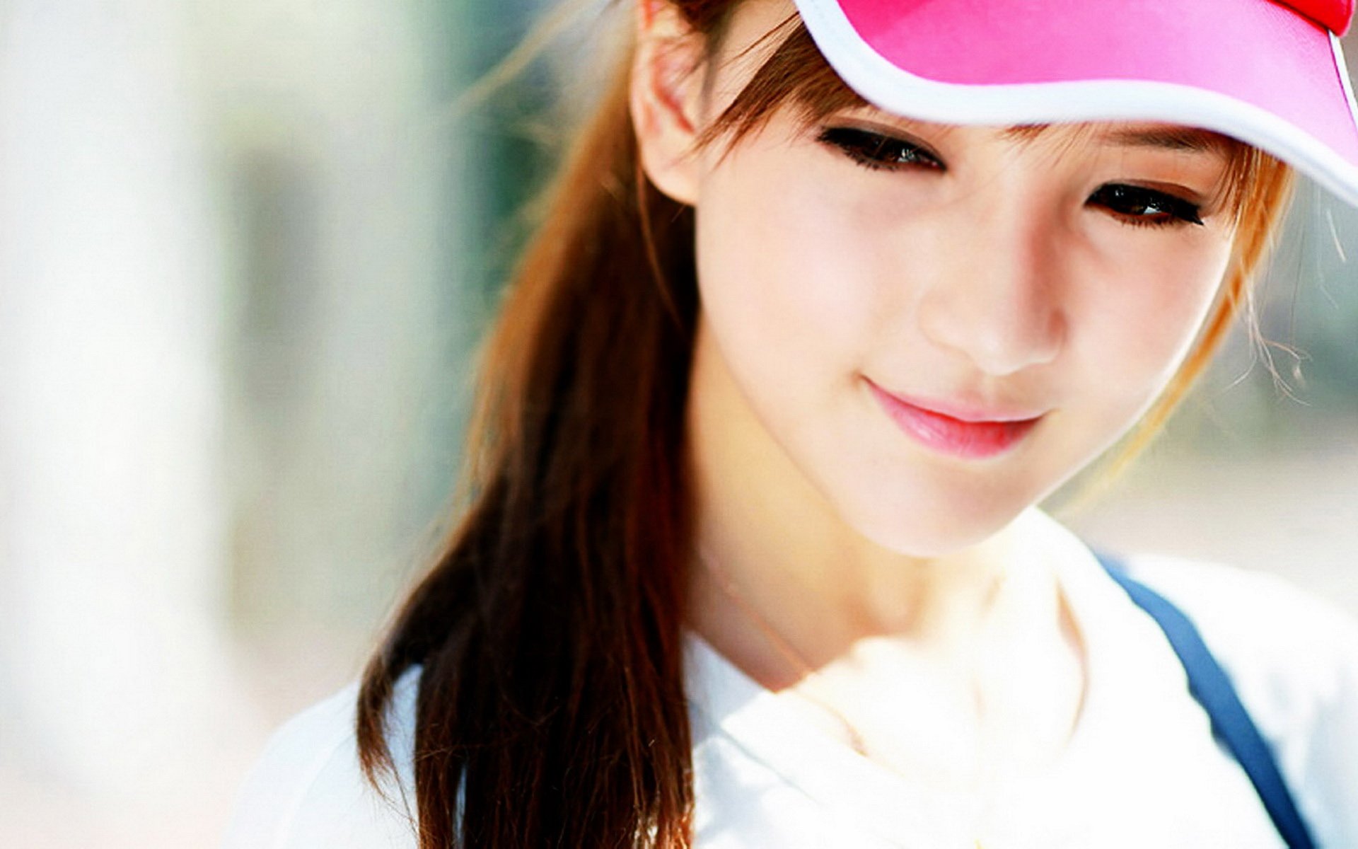 HD PC desktop wallpaper showing a smiling female model in a pink visor, soft-focus bright background.