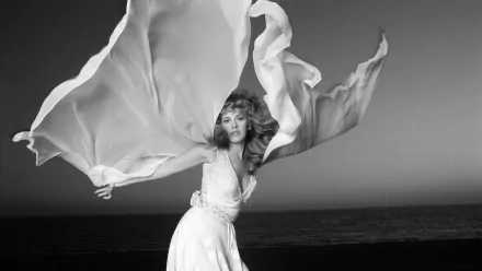 Black and white HD desktop wallpaper of American Fleetwood Mac singer Stevie Nicks with long flowing hair and a billowing dress against a dark background.