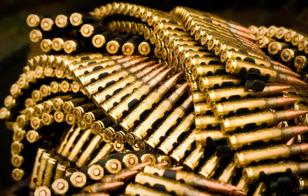 A close-up view of intricately arranged bullets, showcasing military gear with a focus on the craftsmanship of man-made ammunition in vibrant gold and black tones.