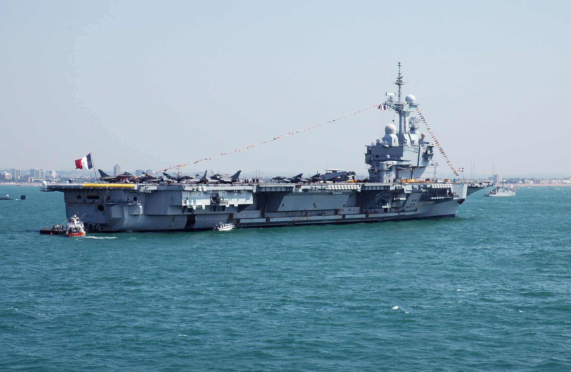 HD desktop wallpaper featuring the French aircraft carrier Charles De Gaulle (R91) warship sailing on calm waters with a clear sky backdrop.