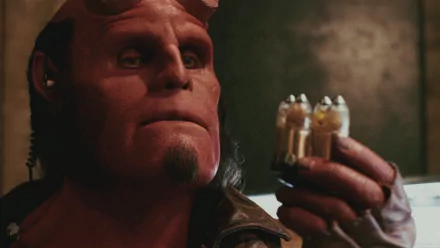 Hellboy from the 2004 movie, portrayed by Ron Perlman, holding three bullet-like objects. This image is a HD desktop wallpaper and background.