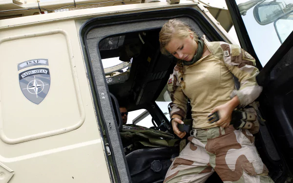 A soldier in military camouflage climbs out of a vehicle, showcasing the dedication and resilience of service members. This HD desktop wallpaper captures the essence of military life.