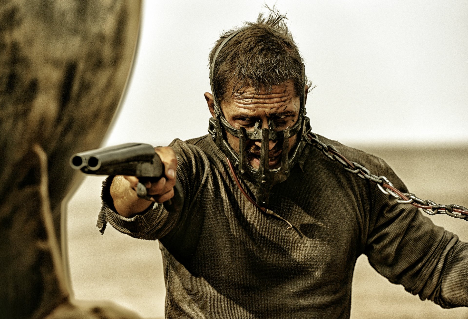 Max Rockatansky, portrayed by Tom Hardy, fiercely aims his weapon in a gritty scene from *Mad Max: Fury Road*, showcasing intense action in stunning 4K Ultra HD.
