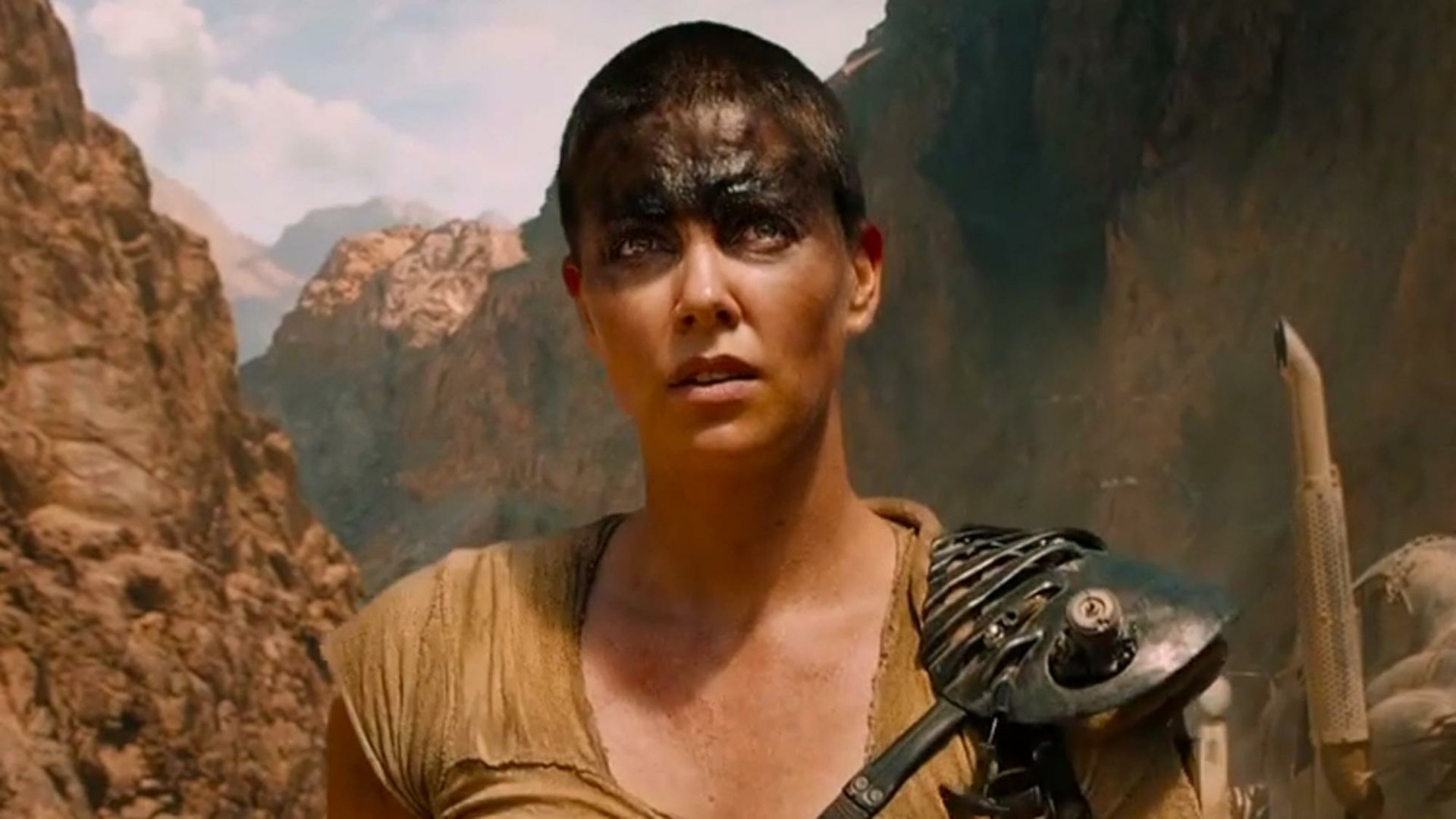 HD PC desktop wallpaper featuring Imperator Furiosa, portrayed by Charlize Theron, from the movie Mad Max: Fury Road in a rugged desert setting.