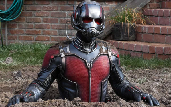 HD PC desktop wallpaper featuring Ant-Man from the movie, emerging from a patch of dirt with a brick wall and plants in the background.