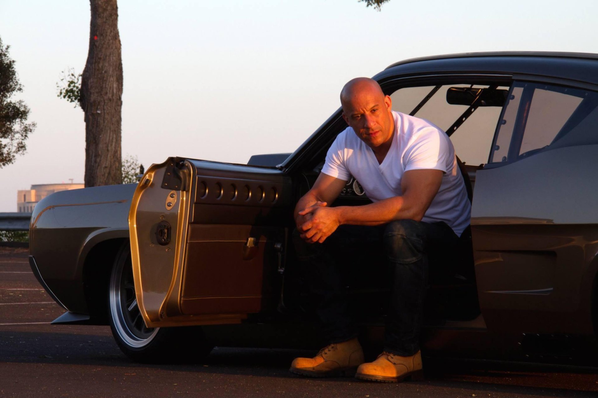 Vin Diesel as Dominic Toretto in Furious 7, crouching by a car with an open door, featured in a HD desktop wallpaper and background.