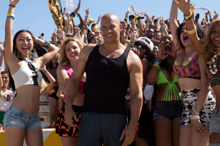 Dominic Toretto, played by Vin Diesel, smiles amidst a vibrant crowd in this HD wallpaper from the movie Furious 7. A dynamic scene capturing energy and excitement.