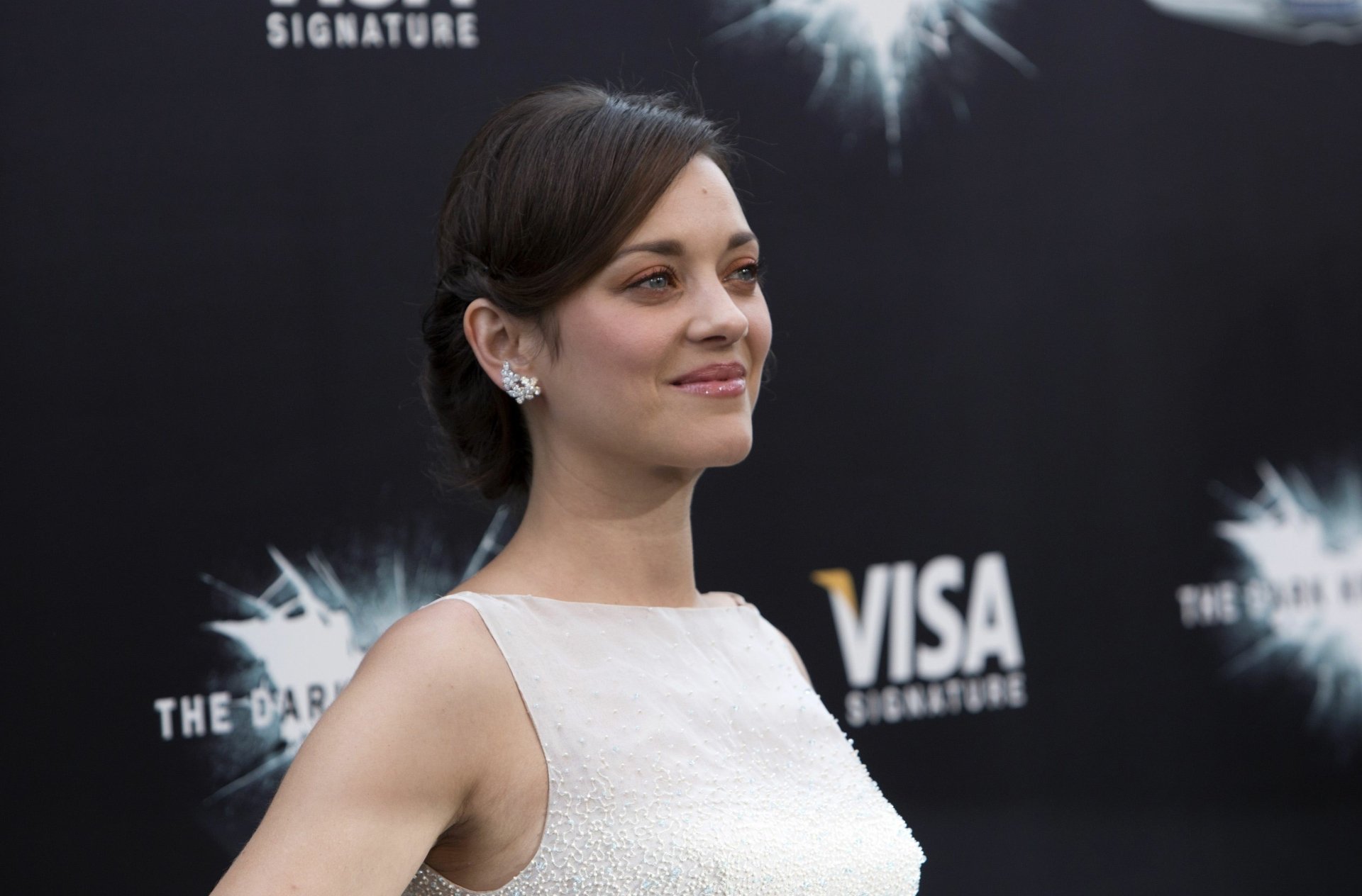 Smiling woman in a white dress on a dark event backdrop, captured as a 2K Quad HD PC desktop wallpaper/background.