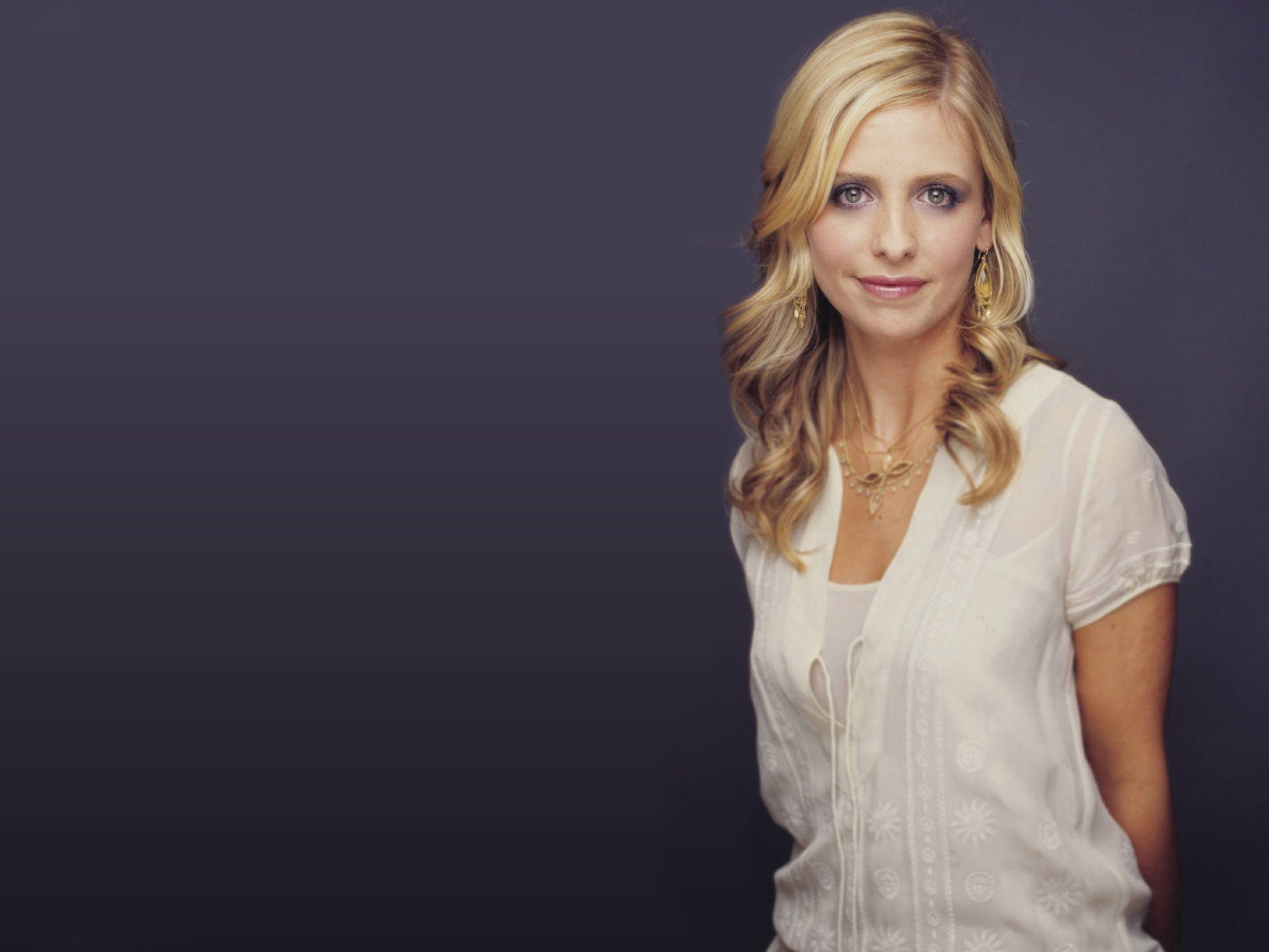 HD desktop wallpaper featuring celebrity Sarah Michelle Gellar in a white blouse against a dark gradient background.