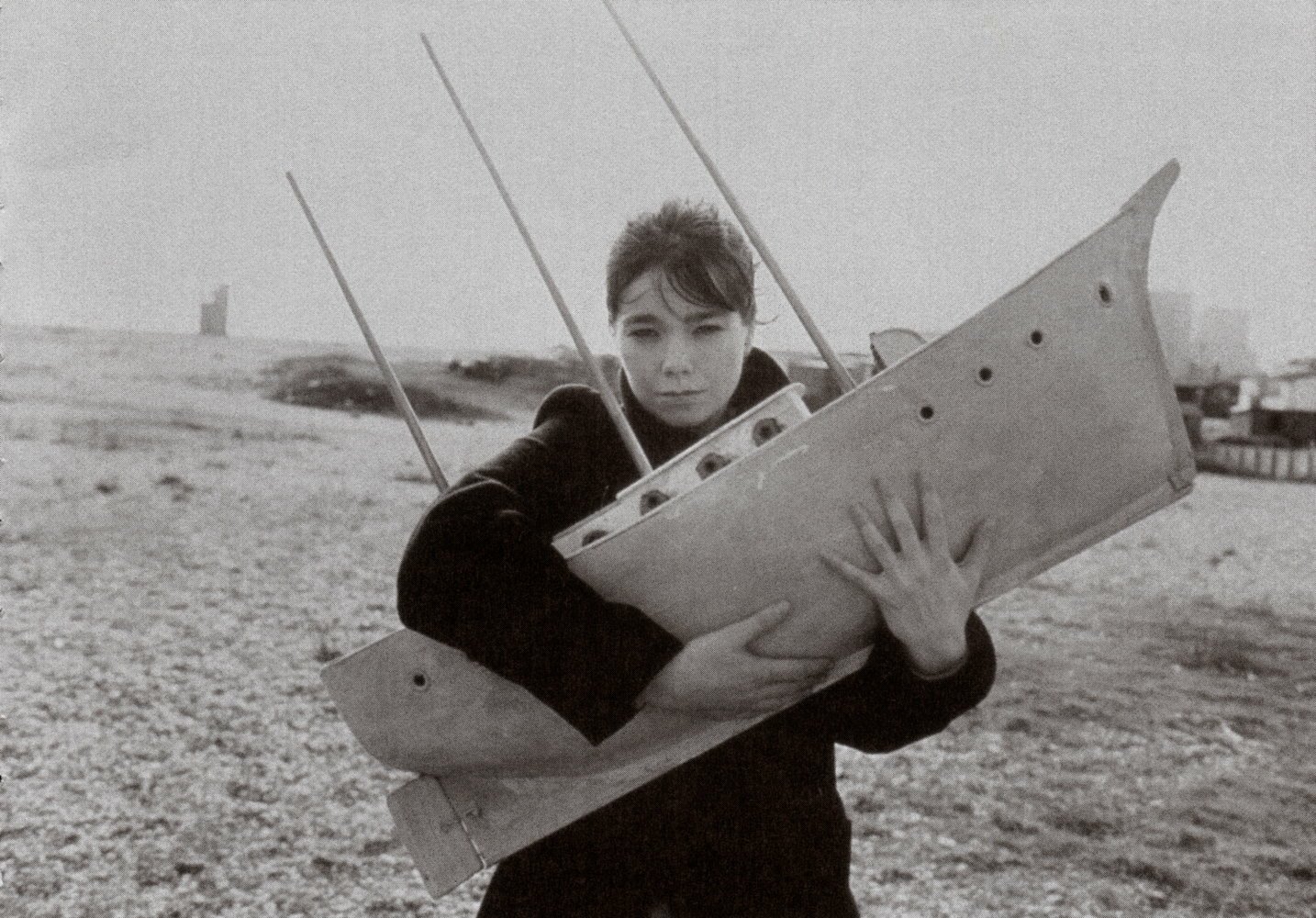 Black and white HD PC desktop wallpaper of Björk holding a large wooden object on a beach, blending music and artistic expression.
