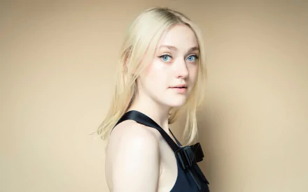 HD desktop wallpaper featuring celebrity Dakota Fanning with a neutral beige background, showcasing her light hair and blue eyes in a black outfit.