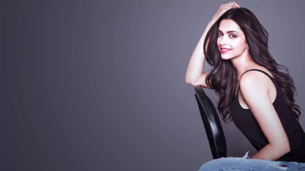 HD desktop wallpaper featuring celebrity Deepika Padukone, posing confidently against a neutral grey background, wearing a black top and jeans.
